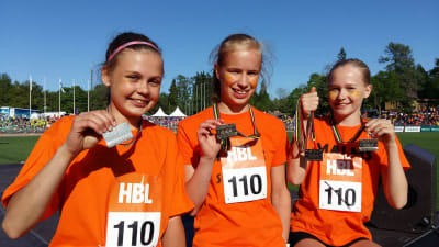 Tre flickor från Malms skola presenterar sina silvermedaljer efter lopp på Stafettkarnevalen. 