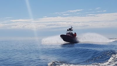 sjöräddningsbåt kör i full fart på solblänkande hav