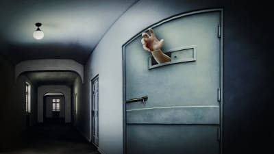 Käsi kurkottaa eristyshuoneen luukusta.
