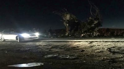 En bil står brevid en buss som har utsatts för en självmordsattack.