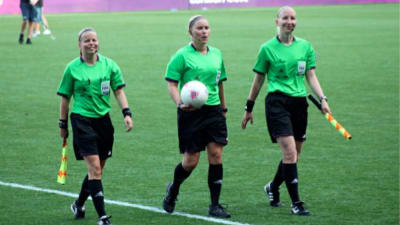Tonja Wecsktröm, Kirsi Heikkinen och Anu Jokela går bredvid varandra invid en fotbollsplan.