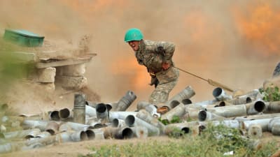 En soldat står bakom en kanon omgiven av tomhylsor och krutrök.