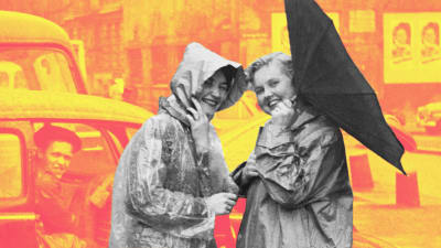 Två kvinnor poserar till kameran i regnkläder och ett vänt paraply i Hamburg. 