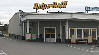 Halpa-Halli i Vörå sett rakt framifrån mot ingången. En stor skylt med logon står uppe på taket av den ganska låga butikslokalen från 70-talet.
