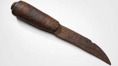 Närbild på gammal rostig puukko-kniv med träskaft. 