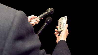 En journalist står med intervjuredskap i handen
