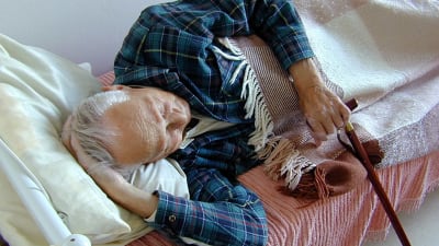 En gammal man vilar i en säng