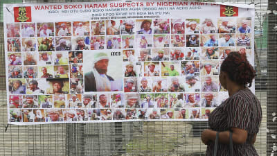 En kvinna tittar på en affisch med bilder av efterlysta misstänkte Boko Haram-anhängare.