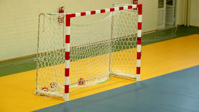 Ett tomt handbollsmål på an handbollsplan inomhus.