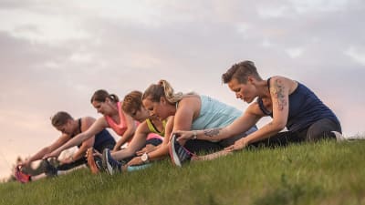 Människor gör gymparörelser på en gräslinda.