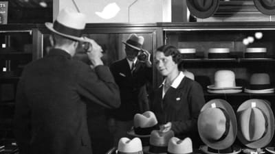 Kundbetjäning på hattavdelningen år 1930. Man köper hatt av kassabiträde i Stockmann.