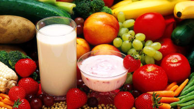 Stilleben av frukt, grönsaker och upphälld sojamjölk och vasslekvarg.