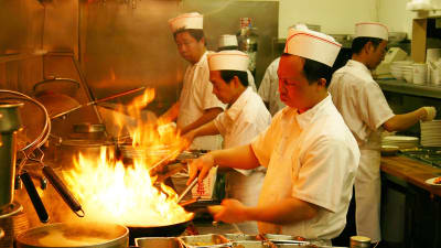 Kinesiska kockar wokar under hög värme.