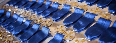 Massor av glittrande medaljer i flera rader med blå medaljband