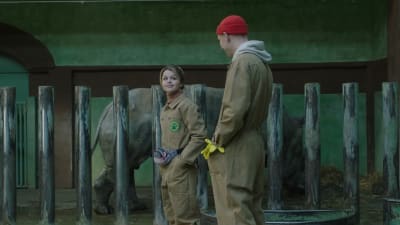 Anya (Lilia Tsvelikova) och Max (Oleksandr Rudynskyi) står och ser på varandra, i bakgrunden syns en noshörning. 