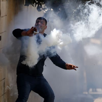 Palestinsk demonstrant i färd med att slänga iväg en gaskanister.