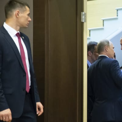 Venäjän presidentti Vladimir Putin ja Turkin presidentti Recep Tayyip Erdoğan keskustelevat kuvan oikeassa laidassa. Vasemmalla etualalla venäläinen henkivartija seisoo oven ulkopuolella.