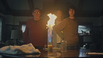 Steve, Annie och Peter står vid ett bord och ser förskräckta ut då ett ljus på bordet flammar upp med en enorm låga.