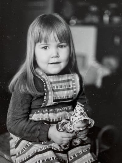 Säveltäjä, muusikko Astrid Swan lapsena mustavalkoisessa valokuvassa nukke käsissään.