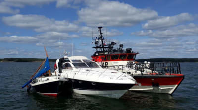 En segelbåt med bruten mast, en motorbåt och Sjöräddningens båt guppar bredvid varandra på havet. I en kollision mellan motorbåten och segelbåten dog personer.