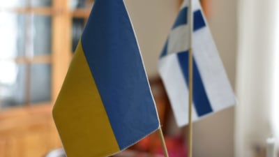 En liten ukrainsk och en liten finsk flagga på ett bord.