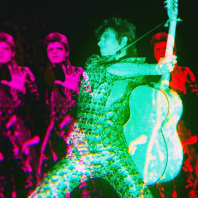 David Bowien vihreäksi sävytetty hahmo kitara kädessä, taustalla monistettuna punaisia Bowie.hahmoja; kuva elokuvasta Moonage Daydream.