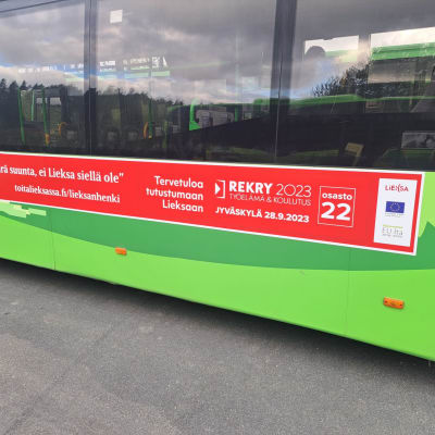 Mainos vihreän linja-auton kyljessä.