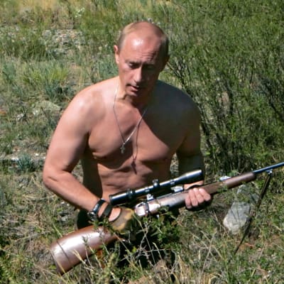 Vladimir Putin ilman paitaa ottaa aurinkoa rannalla.
