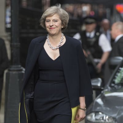 Storbritanniens nya premiärminister Theresa May anländer till 10 Downing Street i silversmycke ler mot kameran.