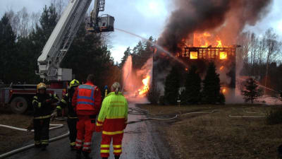 Räddningsmanskap arbetar vid ett brinnande hus.