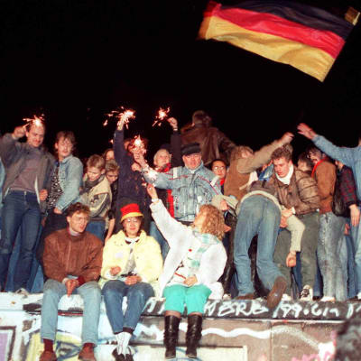 Ihmiset juhlivat Berliinin muurilla.