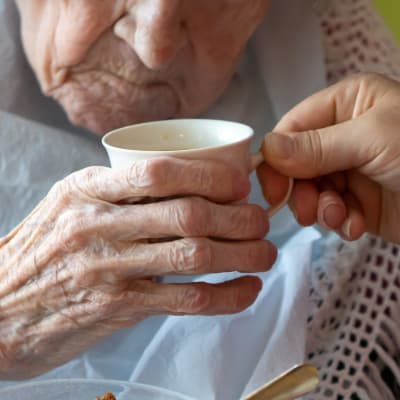 Närvårdare hjälper äldre person att äta. 