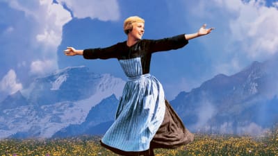 Maria (Julie Andrews) slår ut med armarna och ler uppe på ett berg.