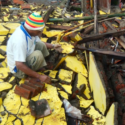 En man inspekterar ruinerna efter sitt kollapsade hus.
