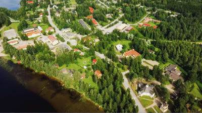 Ilmakuva Sumiaisten kylästä, näkyy kylää halkova Sumiaisraitti, sen varrella rakennusten kattoja, metsää, järvenrantaa