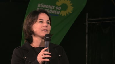 De grönas partichef talar i en mikrofon i samband med valkampanj