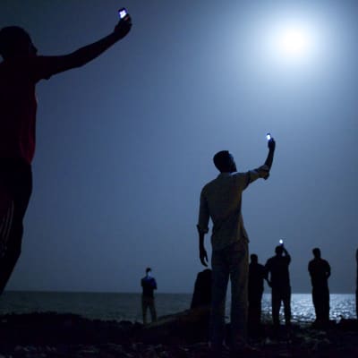 World Press Photo of the Year 2013. Afrikanska migranter i Djibouti försöker nå en mobilsignal från Somalia där priserna är billigare.