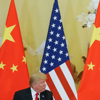 Donald Trump och Xi Junping tittar på varandra med ländernas flaggor i bakgrunden.