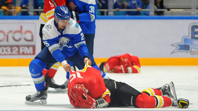 Ishockeyspelaren Damyr Ryspajev drar i skjortan på en motståndarspelare som ligger hjälplös på isen.