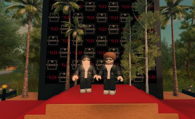 YleX:n Viki ja Köpi seisovat virtuaalihahmoina valokuvausseinän edessä.