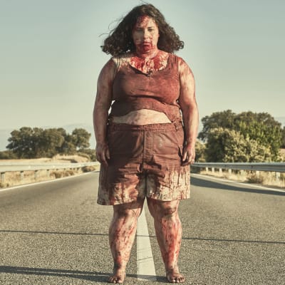 Sara (Laura Galán) står blodig mitt på vägen och ser rakt in i kameran.