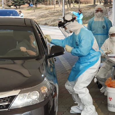 Terveydenhuollon työntekijä ottaa koronavirustestiä autonsa ikkunan avanneelta henkilöltä Cheonanissa Etelä-Koreassa 29. helmikuuta 2020.