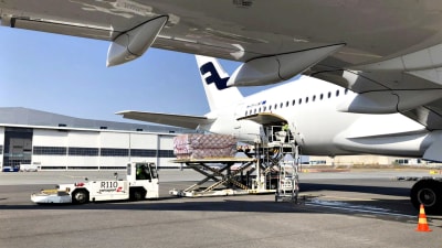 Bild på vitt Finnair-flygplan. På bilden lastas materiel ut ur planet. 