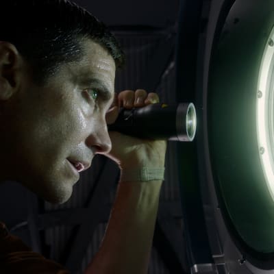David (Jake Gyllenhaal) blinkar med ficklampa ut genom fönstret på rymdstationen.