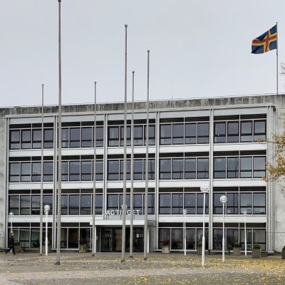 Lagtingets marmorhus i Mariehamn i höstregn, med Ålands flagga på taket