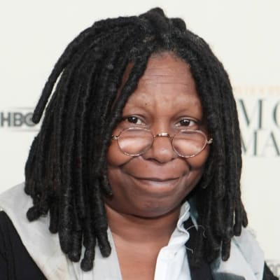 Whoopi Goldberg tittar in i kameran. Hon är fotograferad framför en vit vägg.
