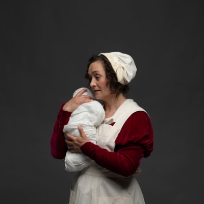 Barnmorskan håller en nyfödd baby mot sin axel. Skådespelare Nina Hukkinen.