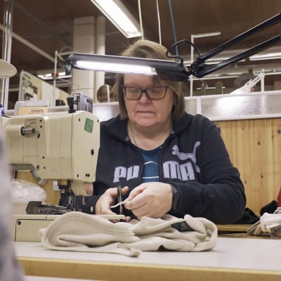 Nainen ompelee villaisia alusasuja Ruskovillan tehtaalla.
