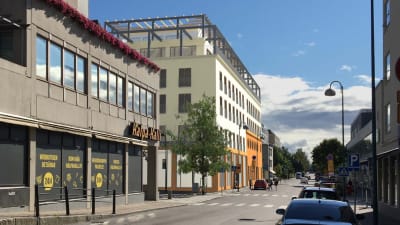 Kvarter med Halpa-Halli i förgrunden och ett digitalt ritat hus i bakgrunden.