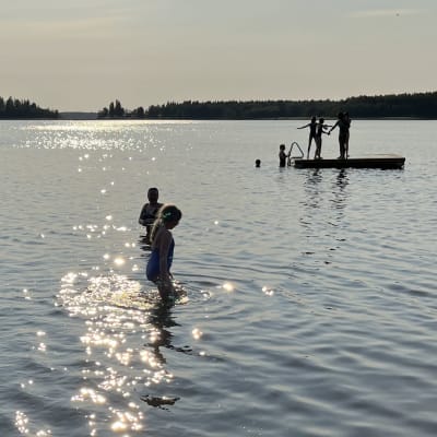 Lapsia uimassa ilta-auringon paisteessa Vikingan rannalla.